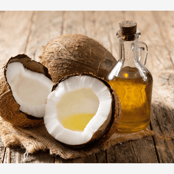 Coconut and a bottle of coconut oil on a wooden surface. A helpful oil for wellness