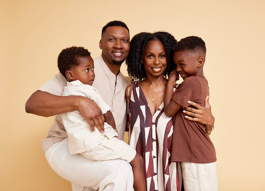 Family of four posing together on a beige background